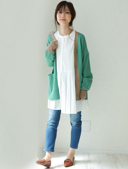 白のブラウスに配色ニットカーディガンを羽織って、スキニーデニムを履く女性