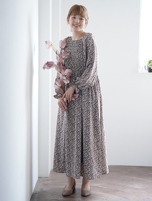 ブラウン系の小花柄マキシ丈ワンピースを着る女性