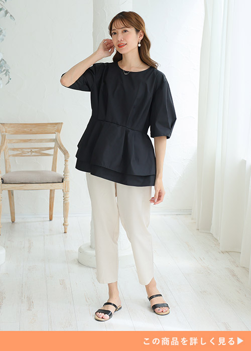 黒のトップス×ホワイトのパンツを着る女性