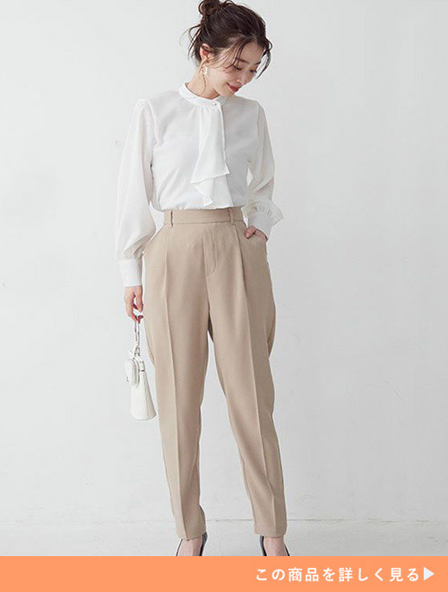 グレージュのテーパードパンツに、白のスカーフタイブラウスをトップスインして着る女性