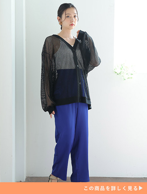 白のキャミソール×鮮やかなブルーのパンツに、黒の透かし編みカーディガンを重ね着する女性