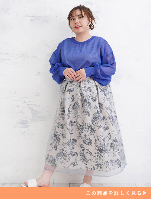 ブルーの透けトップス×オーガンジーを重ねたグレーの花柄スカートを着る女性