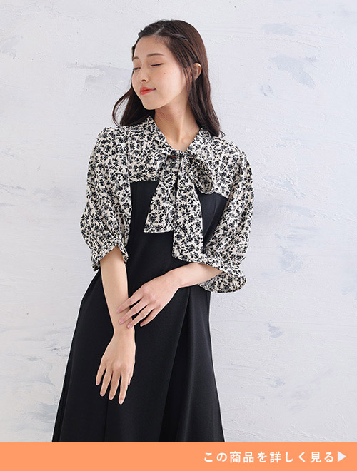 小花柄のボウタイブラウス×ワンピースのレイヤードコーデのようなドッキングワンピースを着る女性