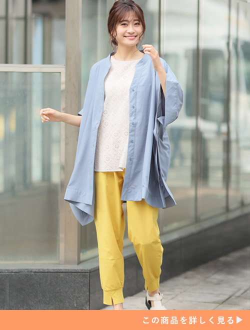 白のレーストップス×イエローのパンツに、くすみブルーのポンチョシャツを羽織る女性