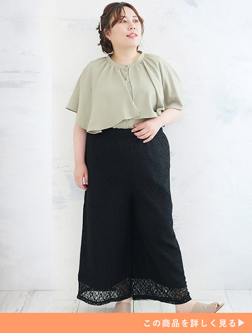 くすみグリーンのブラウスを着て、レース生地のワイドパンツを履く女性