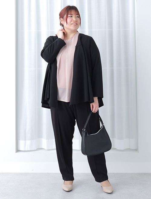 黒のパンツスーツに、ピンクのシフォンブラウスを合わせた女性