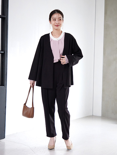 黒のパンツスーツに、ピンクのボウタイブラウスを合わせた女性