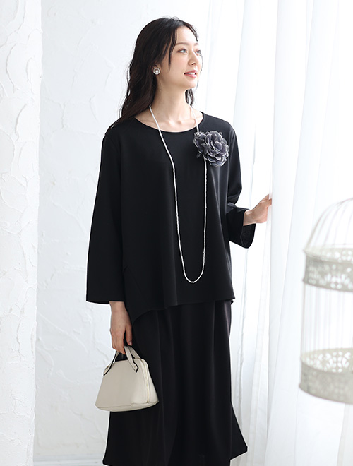 黒のブラウスを着て、同色のスカートを履く女性