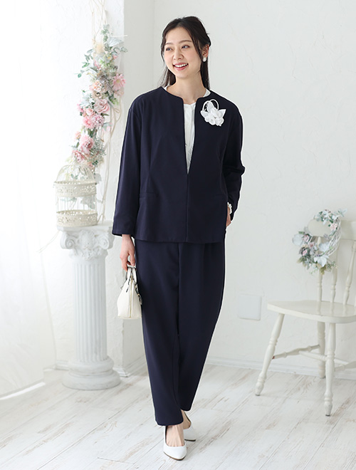 ノーカラーのジャケットとパンツのセットアップを着た女性