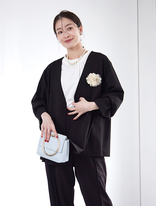 黒のジャケットとパンツのセットアップを着た女性