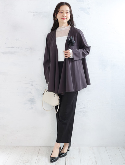 シースルーのトップスに、Vネックのジャケットとパンツのセットアップを合わせた女性