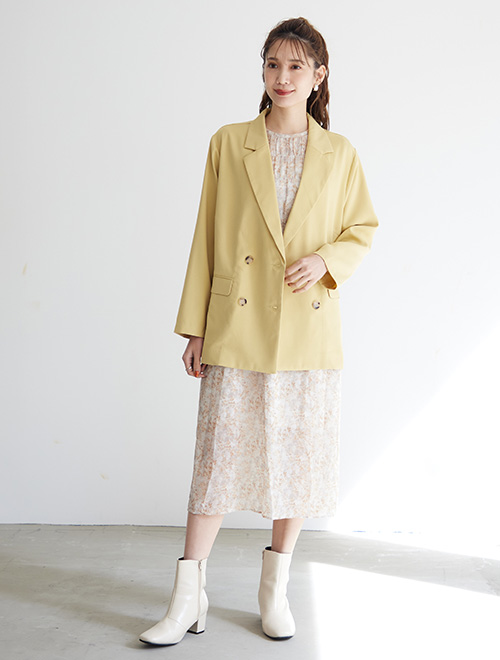 フェミニンな柄ワンピースに、イエローのダブルジャケットを羽織った女性