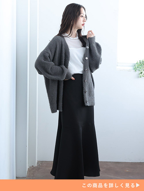 白シアートップス×黒ロングスカートコーデに、グレーのカーディガンを羽織る女性