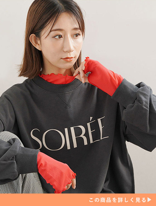 赤のシアートップスにダークグレーのスウェットを重ね着する女性