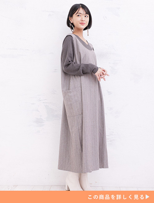 チャコール色のトップスに茶系のロング丈ジャンスカを重ね着する女性