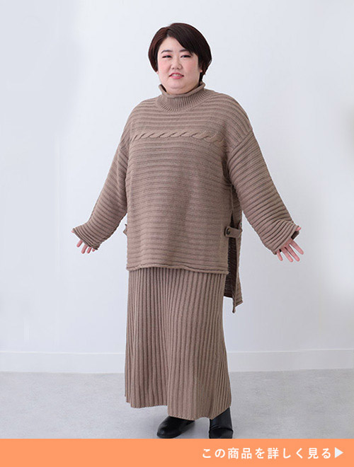 ベージュのニットアップを着る女性。