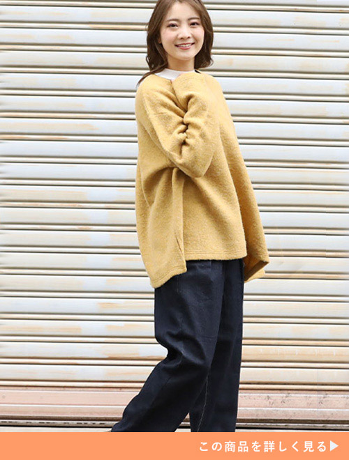 黄色のプルオーバーを着て、コーデュロイパンツを履く女性