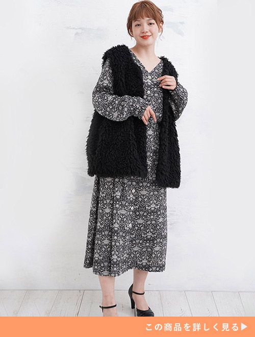 モノトーンの花柄ワンピースに、黒のファーベストを着る女性。