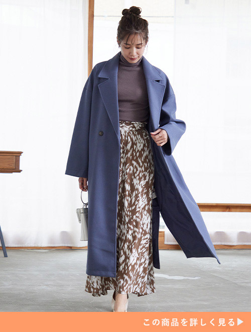 タートルネックニット×ロングスカートのブラウン系ワントーンコーデに、ブルーのテーラードコートを羽織る女性。