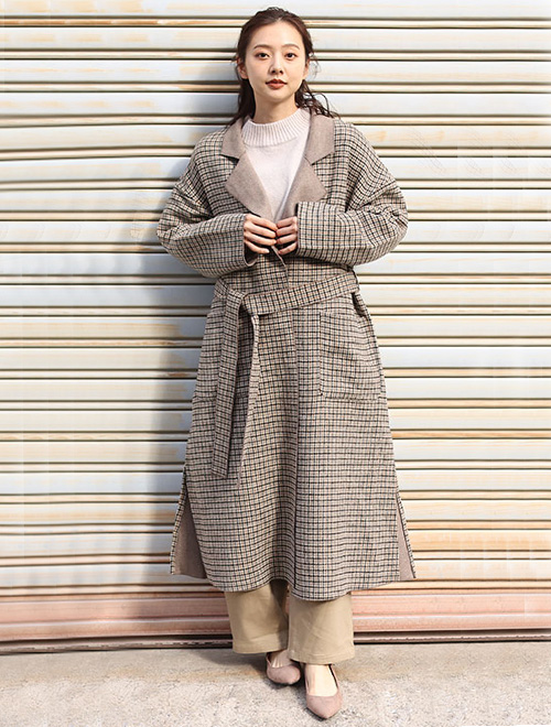 ベージュ系のワントーンコーデに、同色系のチェック柄チェスターコートを羽織る女性