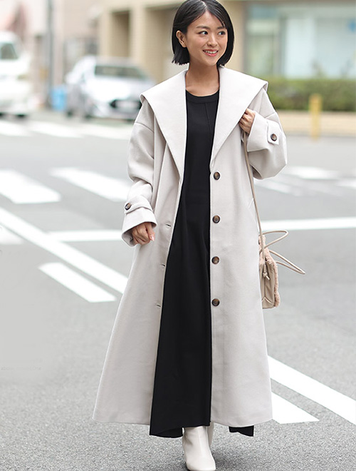 黒のマキシ丈ワンピースに、同じくらいの丈のアイボリーのセーラーカラーコートを羽織る女性
