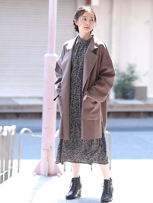 黒の小花柄ワンピースに、ブラウンのミドル丈チェスターコートを羽織る女性
