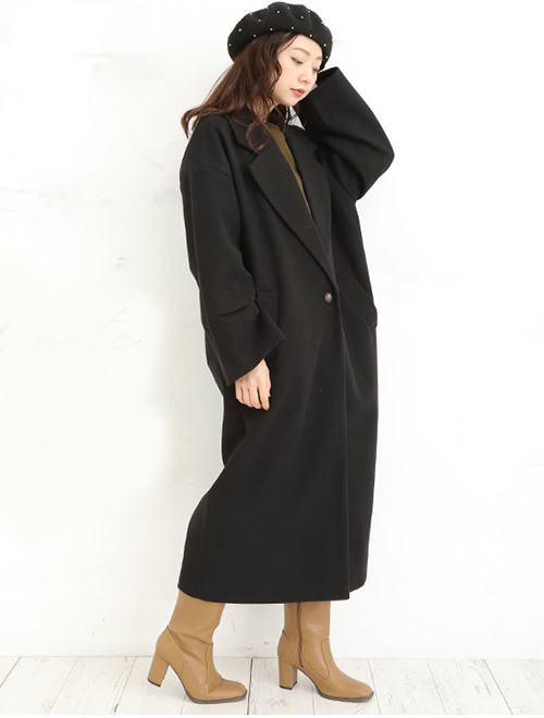 黒のロング丈チェスターコートのインナーにカーキ色トップスを着る女性