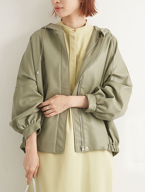 くすみイエローのワンピースにカーキのエコレザーブルゾンを羽織る女性。