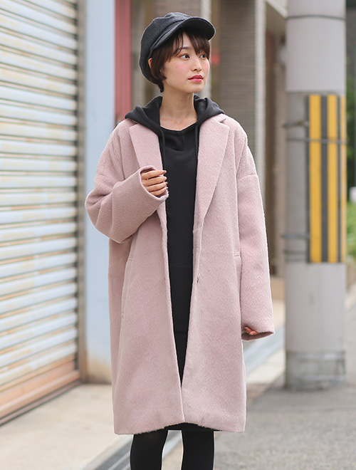 全身黒のワンピース×レギンスコーデに、ピンクベージュのチェスターコートを羽織る女性