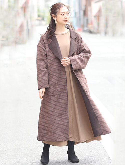 ベージュのワンピースに、ブラウン系のチェック柄チェスターコートを羽織る女性