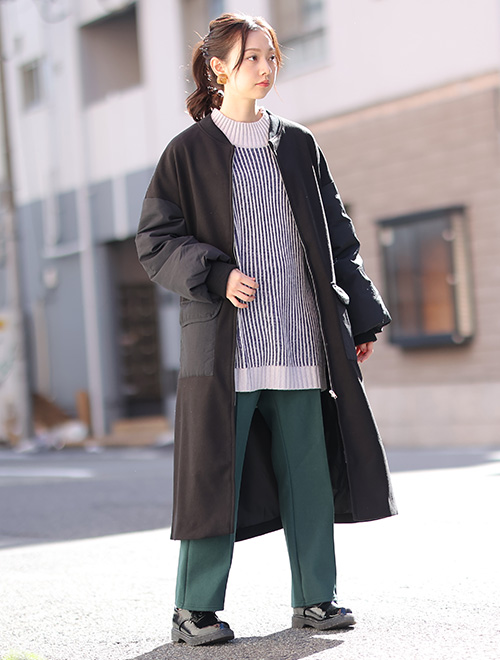 白青のストライプ柄ニット×緑パンツコーデに、黒のMA-1風デザインコートを羽織る女性