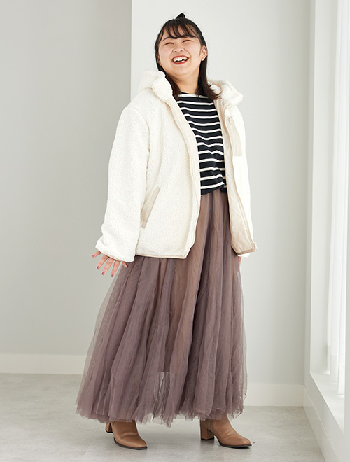ボーダートップス×ロング丈のチュールスカートに、アイボリーのボアジャケットを羽織る女性