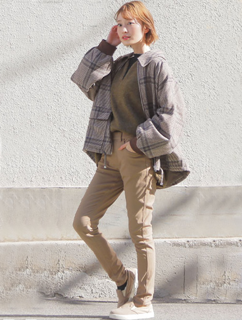 アースカラーのワントーンコーデに、ビッグシルエットのチェック柄ジャケットを羽織る女性