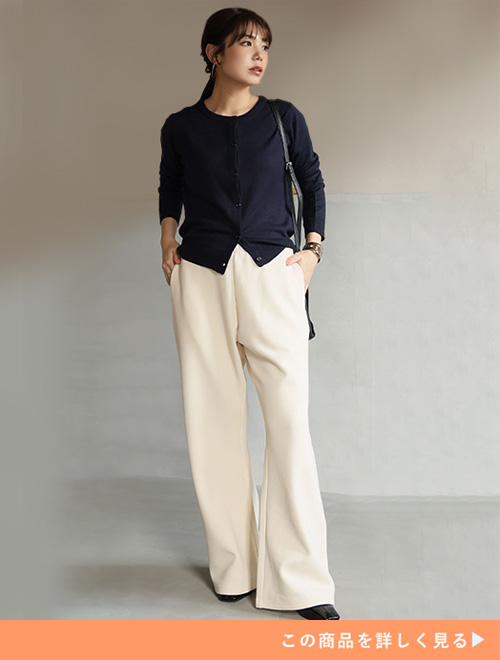 アイボリーのセミフレアパンツにブラックカーディガンを羽織る女性