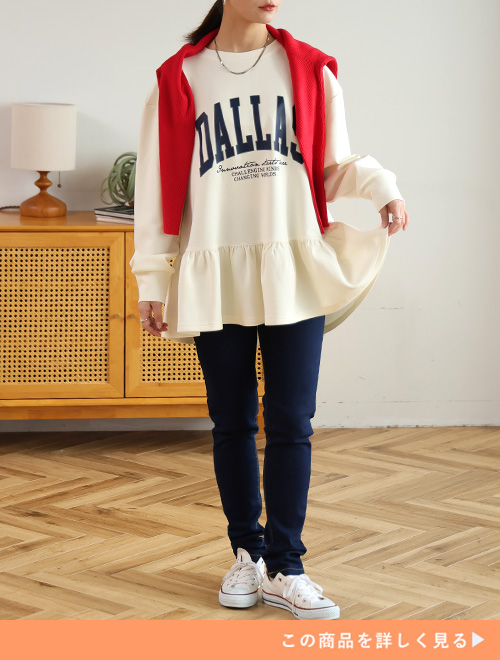 オフホワイトのロゴティアードチュニックとスキニーデニムのコーデにレッドカーディガンを羽織る女性