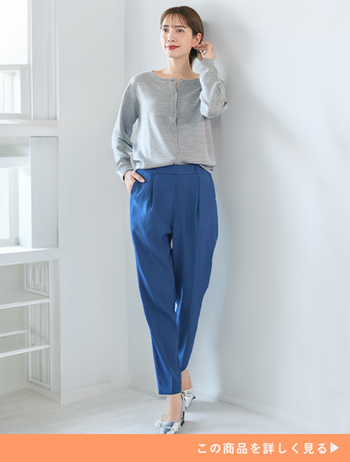 ダークブルーのテーパードパンツとグレーカーディガンのコーデにシルバーパンプスを履く女性