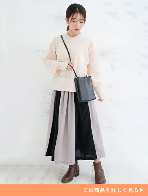 ブラックの切り替えフレアワンピースとホワイトトップスのコーデにブラウンブーツを履く女性