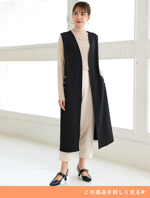 ベージュのパンツとトップスのコーデにブラックロングジレを羽織る女性