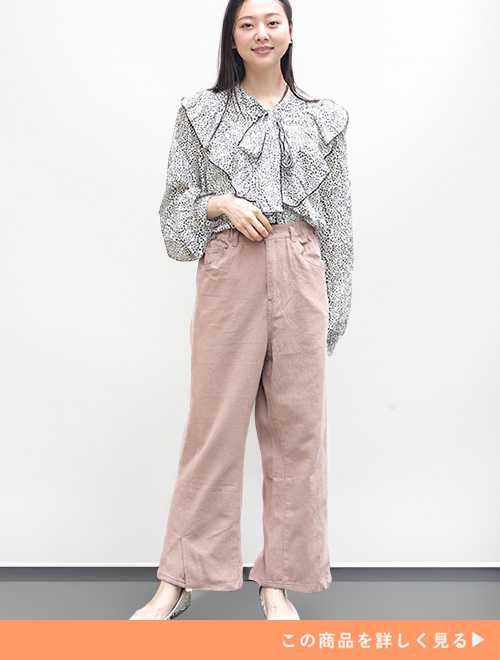 ベージュのフレアーパンツに花柄ブラウスを合わせる女性