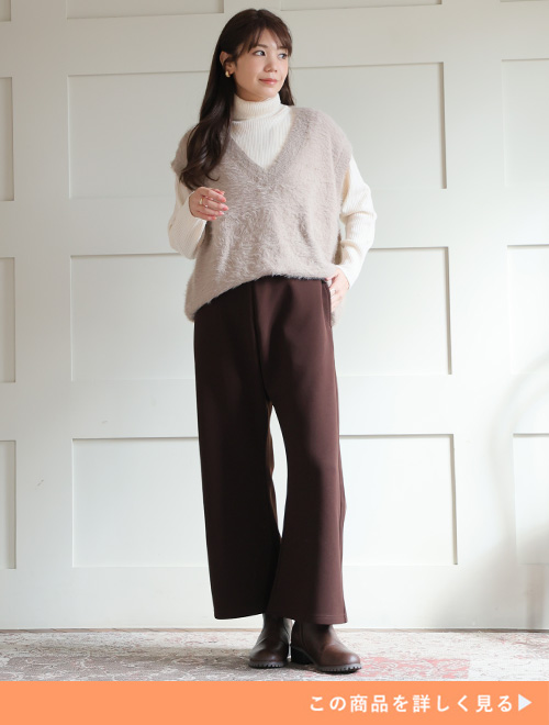 ブラウンのセミフレアパンツとブラウンブーツのコーデにとホワイトタートルニットを合わせる女性