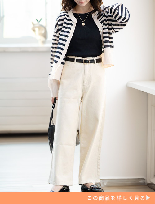 アイボリーのブラックトップスのコーデにボーダーカーディガンを羽織る女性