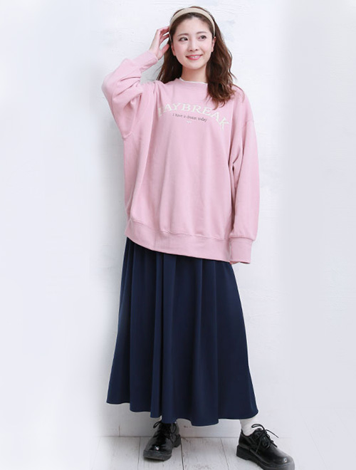 ピンクのトップスとネイビーのロングスカートを履いた女性