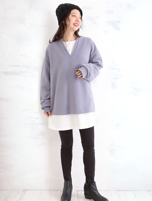 ラベンダーカラーのトップスと黒いボトムスを着た女性