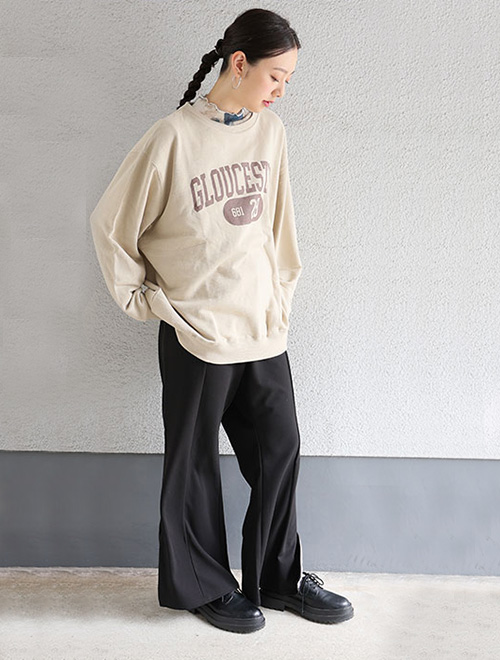 ロゴトレーナーと黒いボトムスを履いた女性