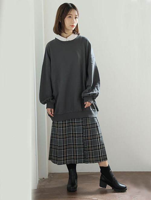 ネイビーのトップスとチェックのスカートを履いた女性が左前を見ている