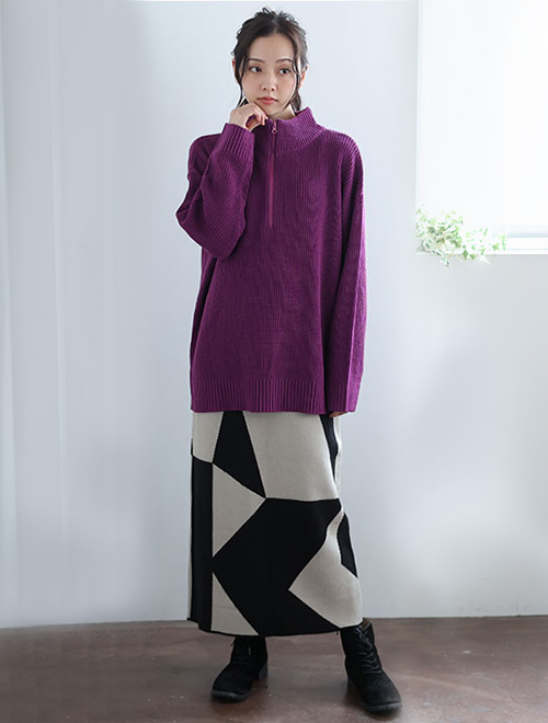 パープルのトップスとモノトーンのスカートを着た女性