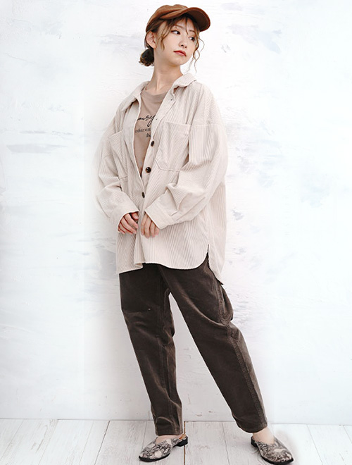 ベージュシャツとブラウンのボトムスを履いた女性