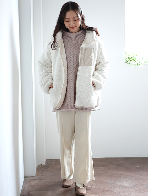 ホワイトコーデでまとめた女性がポケットに手を入れて下を見ている