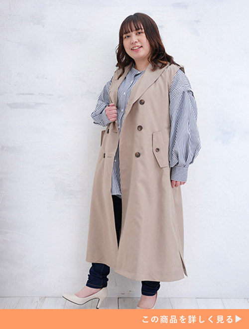 右手でアウターのふちを持つジレをまとった女性