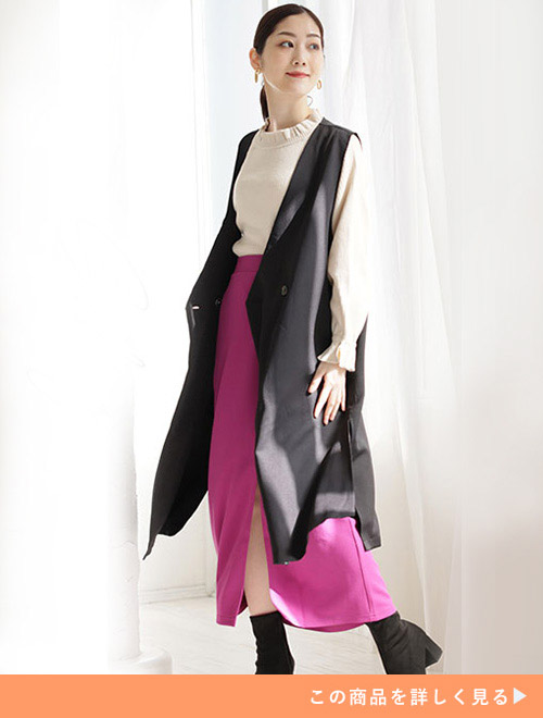 左手を太ももに添えて左側を向く黒いジレを着た女性